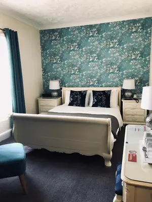 a bedroom with a large bed with a green wall at Lensfield Hotel in Cambridge