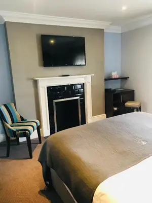 a bedroom with a bed and a fireplace with a flat screen tv at Lensfield Hotel in Cambridge