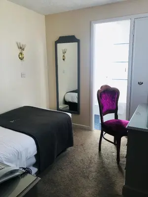 a bedroom with a bed and a chair and a mirror at Lensfield Hotel in Cambridge
