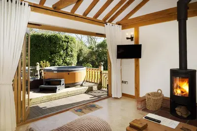 a living room with a hot tub and a fireplace at Owl's Hoot in Thorndon