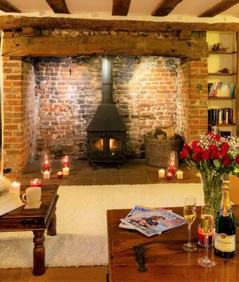 a living room with a fireplace and a table with candles at Oak Cottage in Thorndon