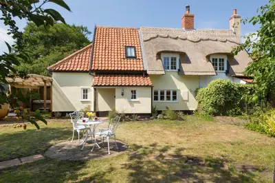 a house with a table and chairs in the yard at Honeysuckle Cottage in Thornham Magna