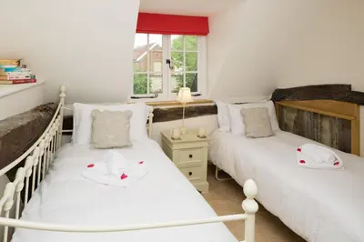two twin beds in a room with a window at Honeysuckle Cottage in Thornham Magna