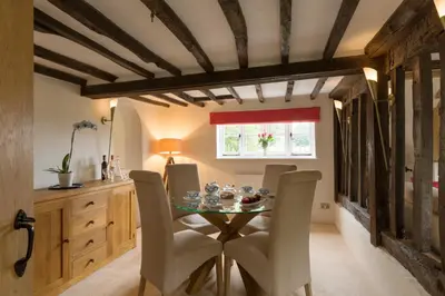 a dining room with a table and chairs at Honeysuckle Cottage in Thornham Magna
