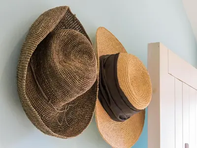two straw hats are hanging on a wall at Bluebell Studio in Saxmundham