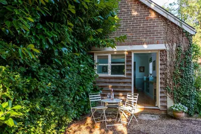 a patio with two chairs and a table in front of a building at Bluebell Studio in Saxmundham