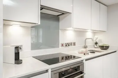 a white kitchen with white cabinets and a sink at Tailored Stays - Central Cambridge Studios, Free Parking in Cambridge
