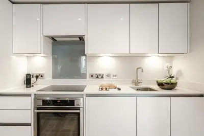 a white kitchen with white cabinets and a sink at Tailored Stays - Central Cambridge Studios, Free Parking in Cambridge