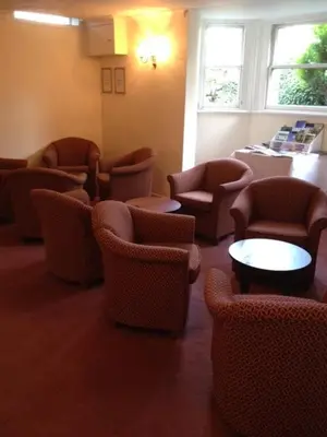 a waiting room with chairs and tables and windows at Ashley Hotel in Cambridge