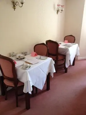 a dining room with two tables with white table cloths at Ashley Hotel in Cambridge
