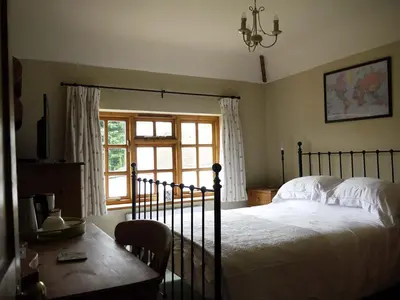 a bedroom with a bed and a table and a window at One Pelham Grove Bed & Breakfast in Stocking Pelham