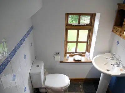 a bathroom with a toilet and a sink and a window at One Pelham Grove Bed & Breakfast in Stocking Pelham
