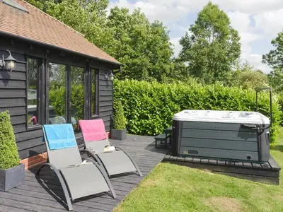 a deck with two chairs and a hot tub at Toad Hall Cottage in Earls Colne