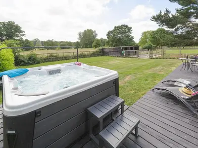 a large bath tub sitting on top of a deck at Toad Hall Cottage in Earls Colne