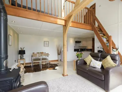 a living room with a couch and a staircase at Toad Hall Cottage in Earls Colne