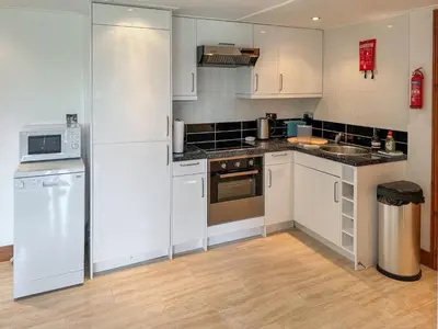 a small kitchen with white cabinets and appliances at Toad Hall Cottage in Earls Colne