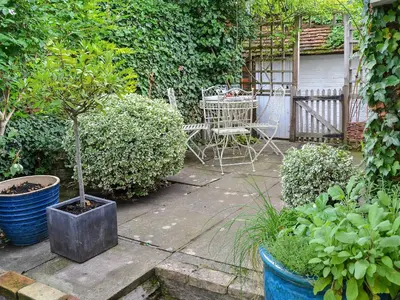 a garden with a table and a chair and a tree at Lavenham Red Brick Cottage in Lavenham