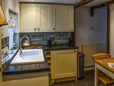 a kitchen with yellow cabinets and a sink at Lavenham Red Brick Cottage in Lavenham