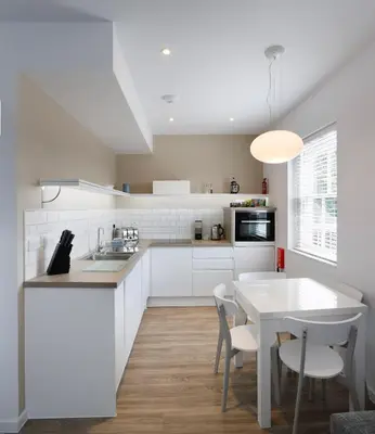 a kitchen with white cabinets and a table and chairs at Citystay Living - Devonshire Road in Cambridge