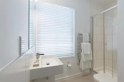 a white bathroom with a sink and a shower at Citystay Living - Devonshire Road in Cambridge