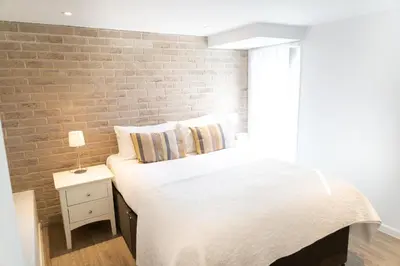 a bedroom with a brick wall and a bed at Citystay Living - Devonshire Road in Cambridge