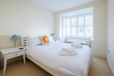 a white bedroom with a white bed and a window at Maisie's in Aldeburgh