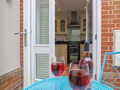 two wine glasses on a table with a bottle of wine at Maisie's in Aldeburgh
