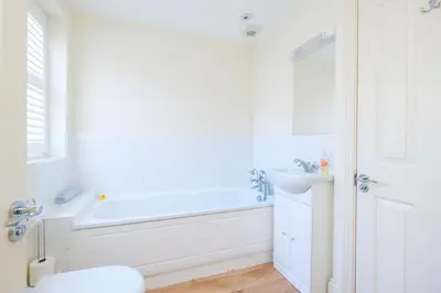 a white bathroom with a tub and a sink at Maisie's in Aldeburgh