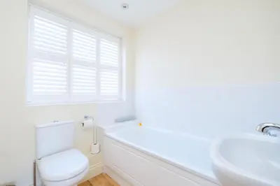 a white bathroom with a toilet and a sink at Maisie's in Aldeburgh