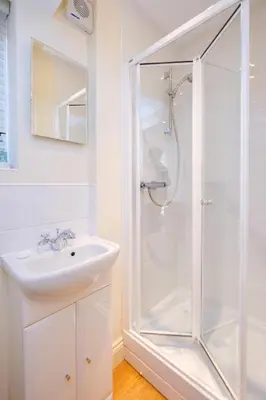 a white bathroom with a shower and a sink at Maisie's in Aldeburgh