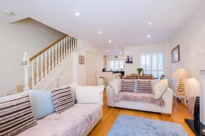 a living room with two white couches and a staircase at Maisie's in Aldeburgh