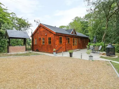 a wooden house with a large yard in front of it at Acorn Lodge in Saxmundham