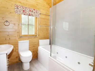 a bathroom with a toilet and a tub and a sink at Acorn Lodge in Saxmundham