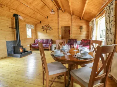 a dining room with a table and a fireplace at Acorn Lodge in Saxmundham