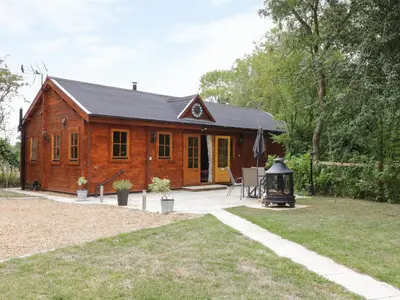 a small wooden cabin with a grill in a yard at Acorn Lodge in Saxmundham