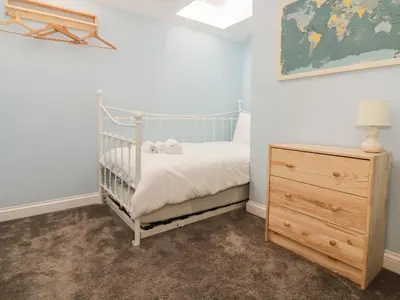 a bedroom with a crib and a wooden dresser at Ploughman's in Eye