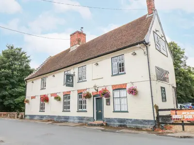 a white building with flowers on the windows at Ploughman's in Eye