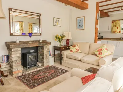 a living room with a couch and a fireplace at Stable Cottage in Sudbury