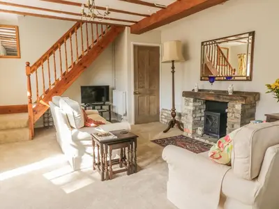 a living room with white furniture and a fireplace at Stable Cottage in Sudbury