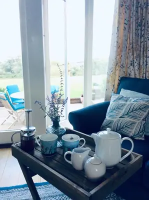 a coffee table with tea sets on it in a living room at Kingfisher Nook at Waveney Farm in Hoxne
