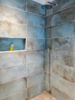 a bathroom with a shower with a tile wall at Robin's Egg in Aldeburgh