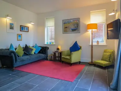 a living room with two couches and a red rug at Robin's Egg in Aldeburgh