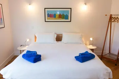 a bedroom with a white bed with blue pillows on it at Robin's Egg in Aldeburgh
