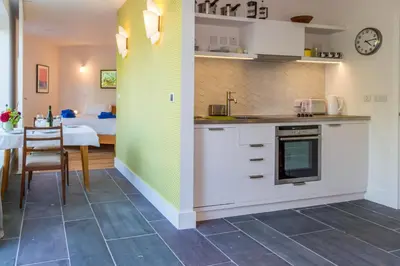 a kitchen with white cabinets and a dining room with a table at Robin's Egg in Aldeburgh