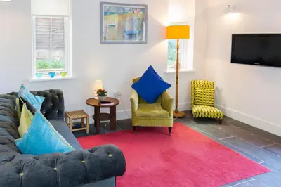 a living room with a couch and chairs and a tv at Robin's Egg in Aldeburgh