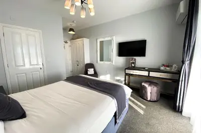 a bedroom with a bed and a dresser and a television at The Royal Hotel - Clacton On Sea in Clacton-on-Sea