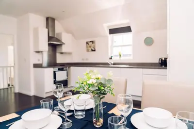 a dining room table with glasses and a vase of flowers at Detached Coach House in Colchester