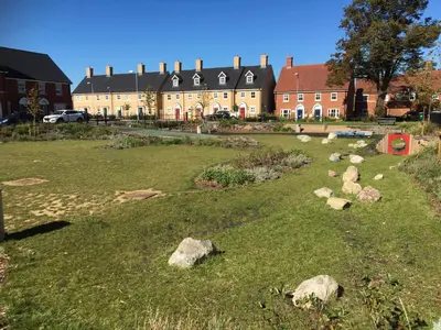 a field of grass with rocks in front of a building at Detached Coach House in Colchester