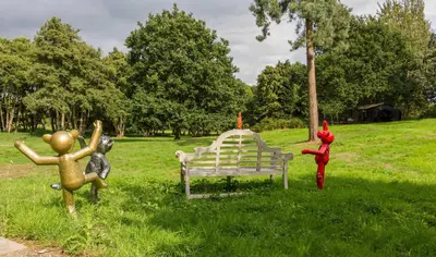 a park with statues of people around a bench at Briar Hill in Aldringham