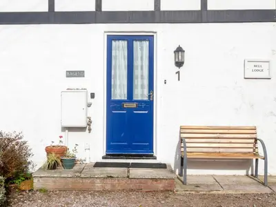 a blue door and a bench in front of a building at 1 Bell Lodge, Thorpeness in Thorpeness
